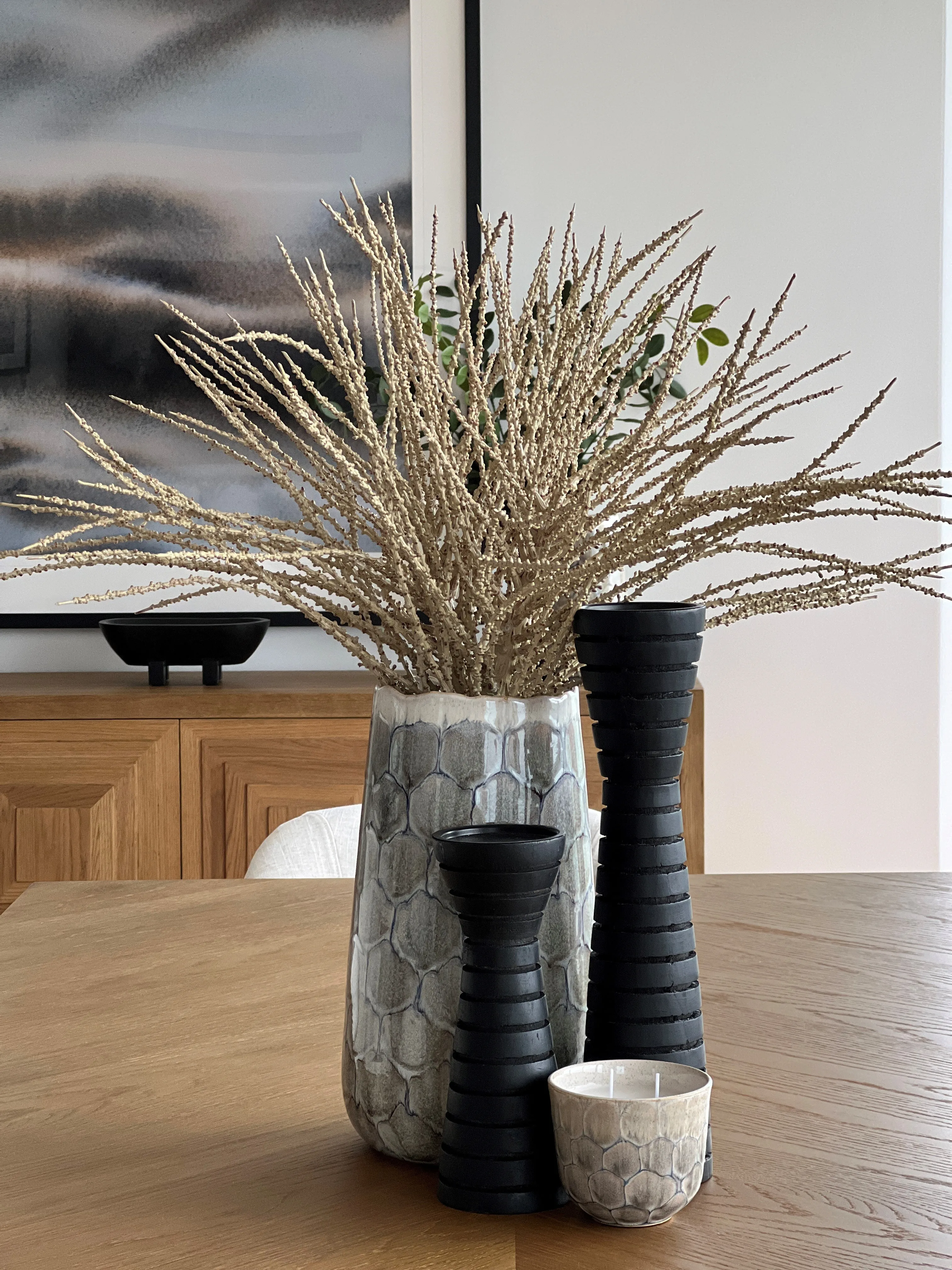 Dining table styling with textured ceramic vases and dried botanicals on oak surface
